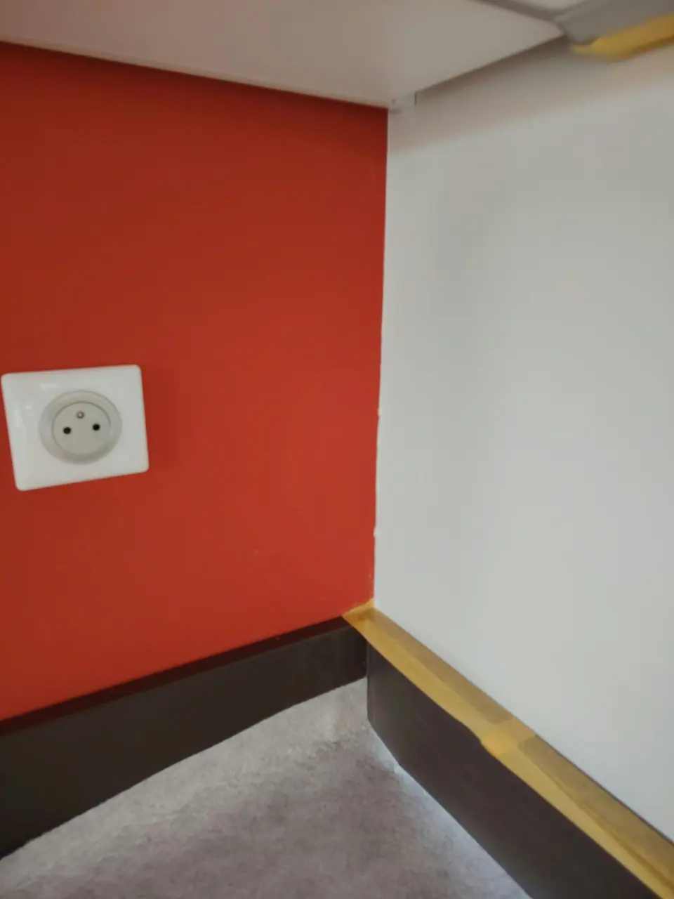 Mur rouge orangé et plinthes repeints