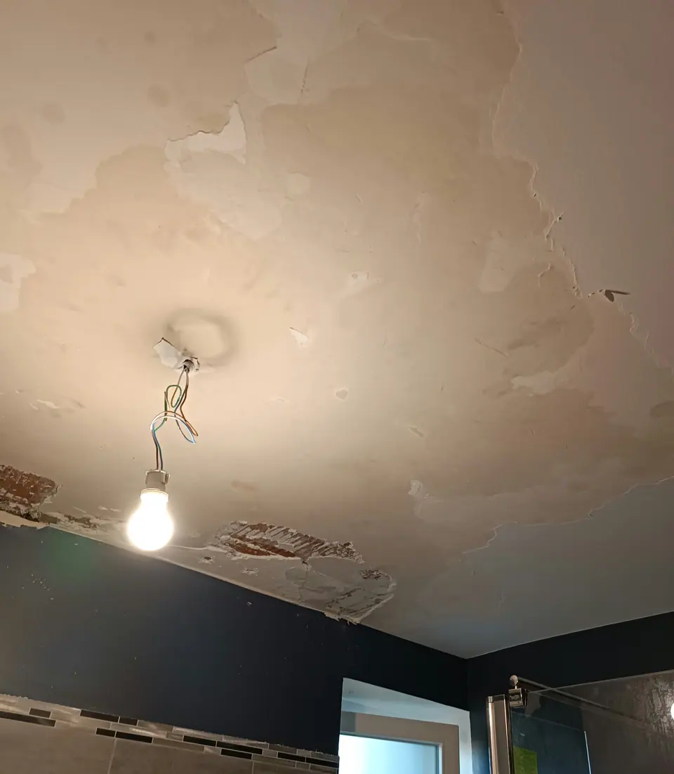 Avant travaux : plafond écaillé au-dessus d'une douche