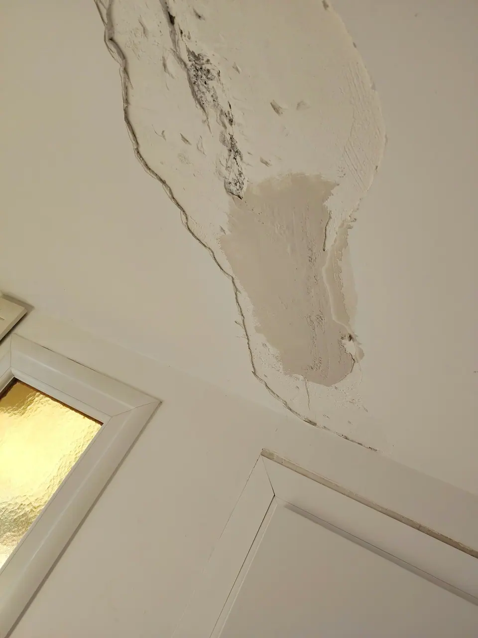 Avant travaux : fissure au-dessus d'une porte vitrée